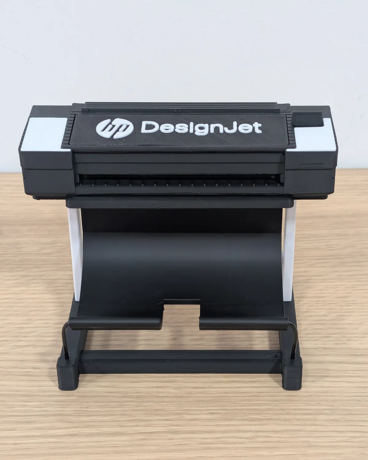 Miniatura del plotter HP DesignJet impresa en 3D en negro y blanco, vista de frente sobre una mesa